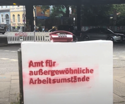 Weiße Box mit Schriftzug Amt für außergewöhnliche Arbeitsumstände steht auf der Straße unter der Sternbrücke in Hamburg.