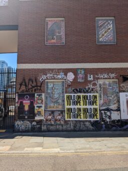 Posterteihe auf einem brownstone Haus, die durch den Slogan "Hold on to Hope" auf gelbem Hintergrund hervorsticht